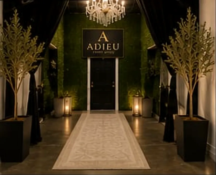 Entrance to Adieu Event Space with greenery wall, chandelier and lit runway